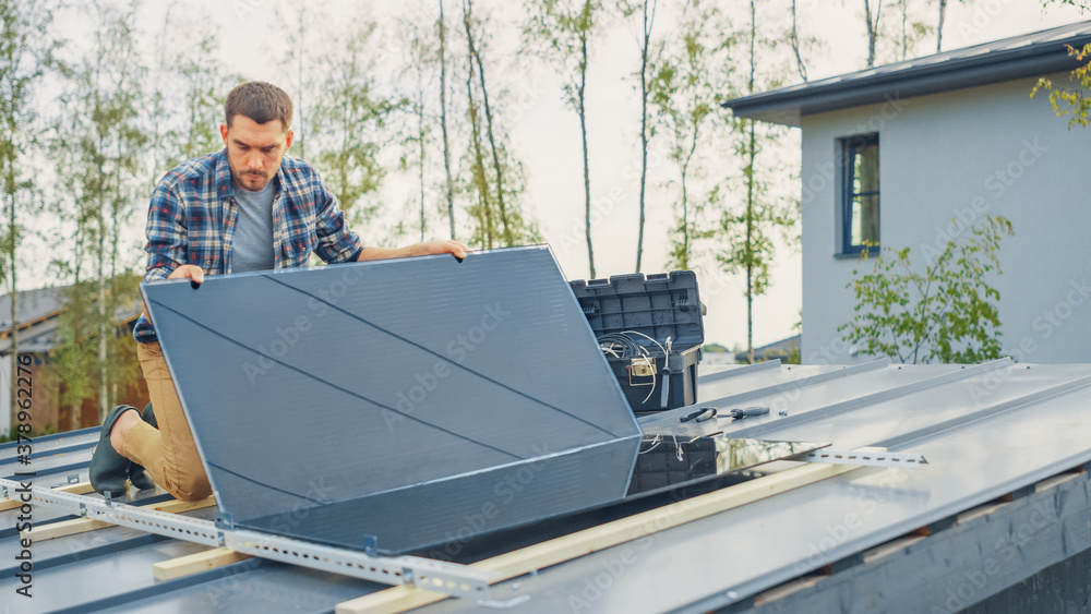 Caucasian Man in Checkered Shirt is Installing Black Reflective Solar Panels on a Metal Basis. He Wo