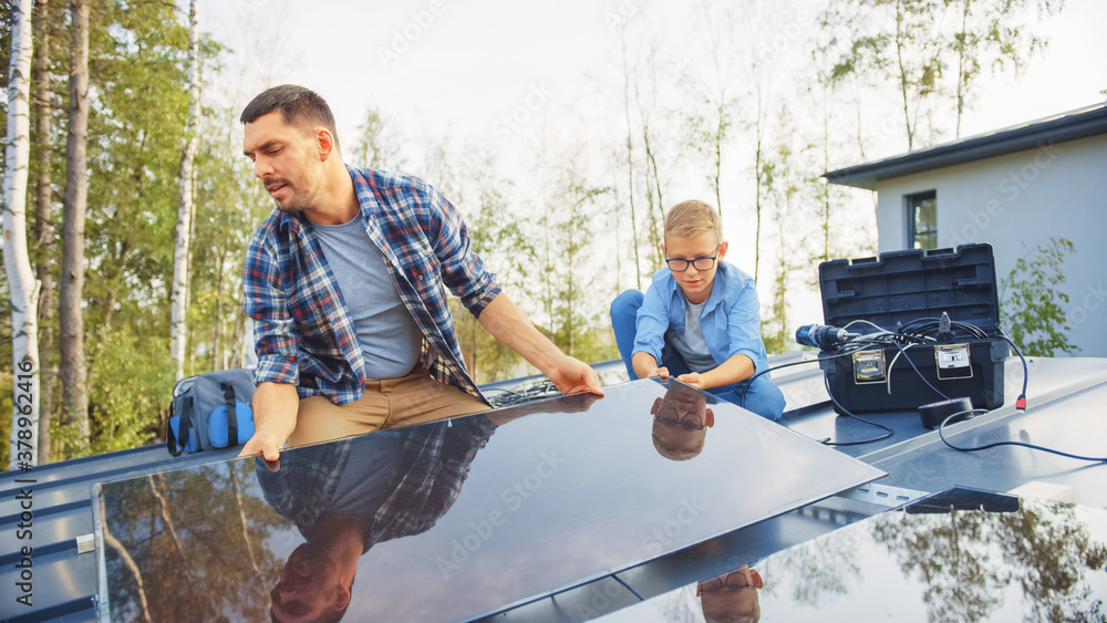 Father and Son Installing Solar Panels to a Metal Basis. They Work on a House Roof on a Sunny Day. C