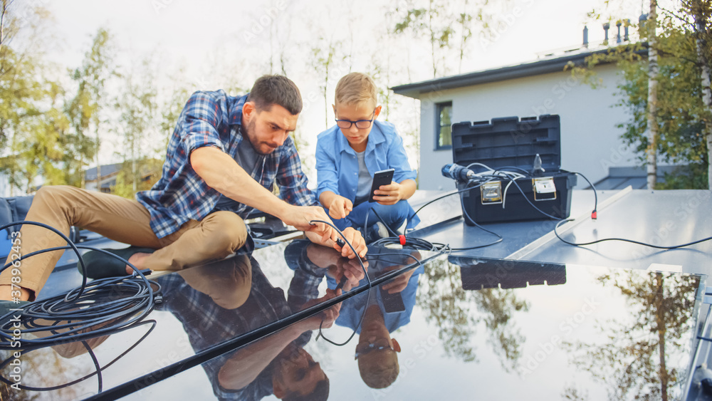 Father and Son Installing Solar Panels to a Metal Basis. They Work with Wiring on a House Roof on a 