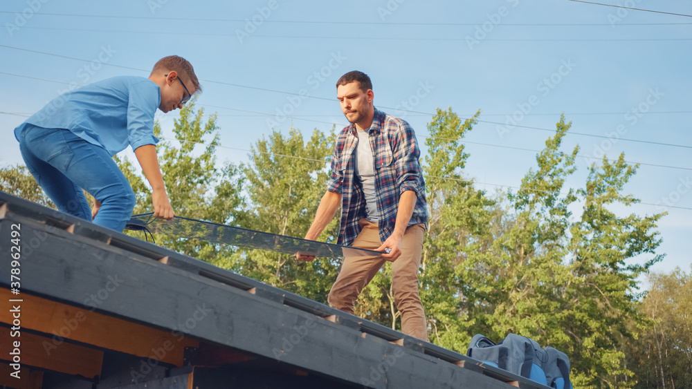 Father and Son Installing Solar Panels to a Metal Basis. They are Holding the Panels on a House Roof