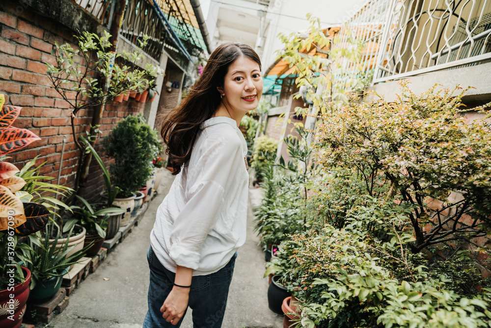 young beautiful asian japanese girl walking in little walkway surrounding by red brick old house in 