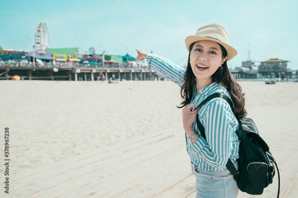 Beautiful young woman with backpack having fun at amusement park. relaxation in spring sandy beach c