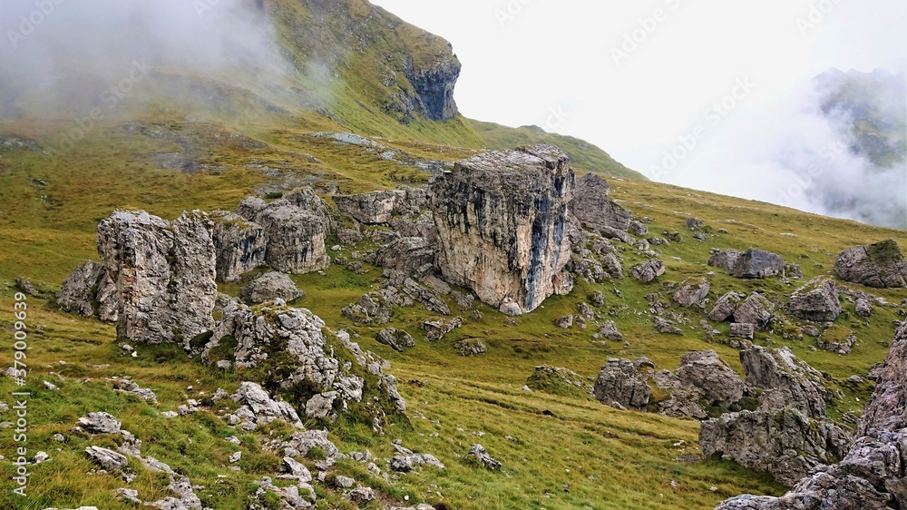 Northern Italy Dolomite Alps Landscape. Fog, green mountainside and large boulders