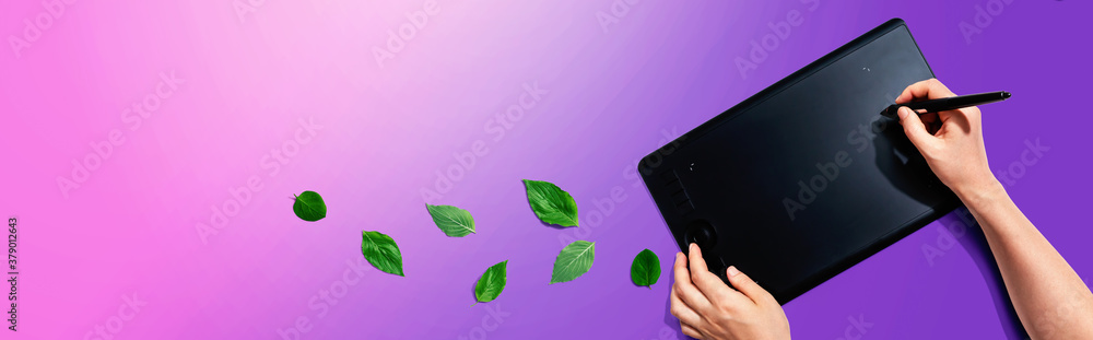 Graphic pen tablet with green leaves - flat lay