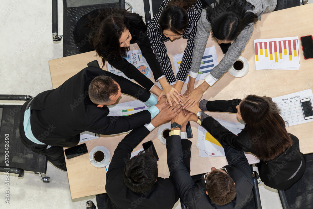 Happy business people celebrate teamwork success together with joy at office table shot from top vie