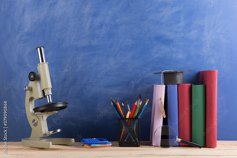 Education and sciences concept - books on the teacher desk in the auditorium, chalkboard on the back