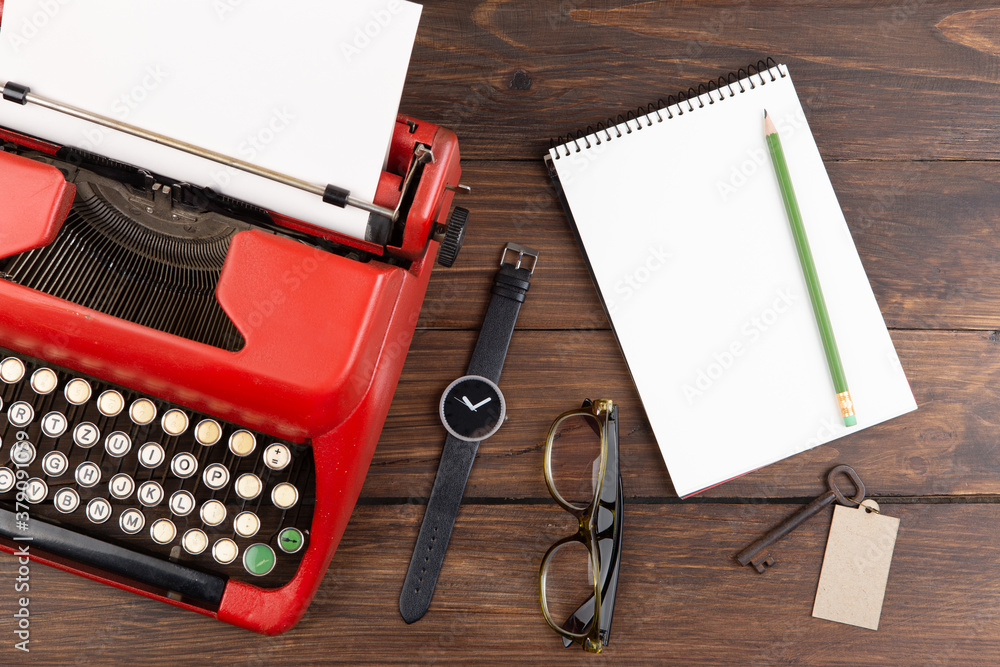 Writer or journalist workplace - vintage red typewriter, glasess and notepad on the wooden desk