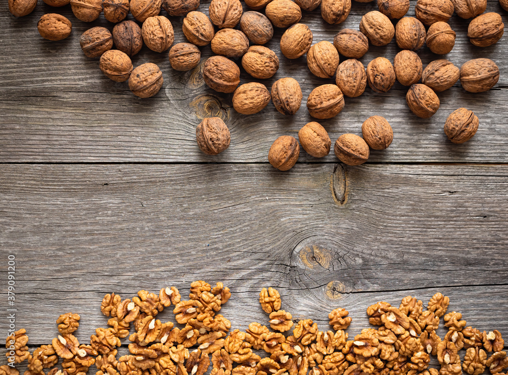 Heap of fresh walnut kernels and whole walnuts on wooden table - natural pattern background detail. 