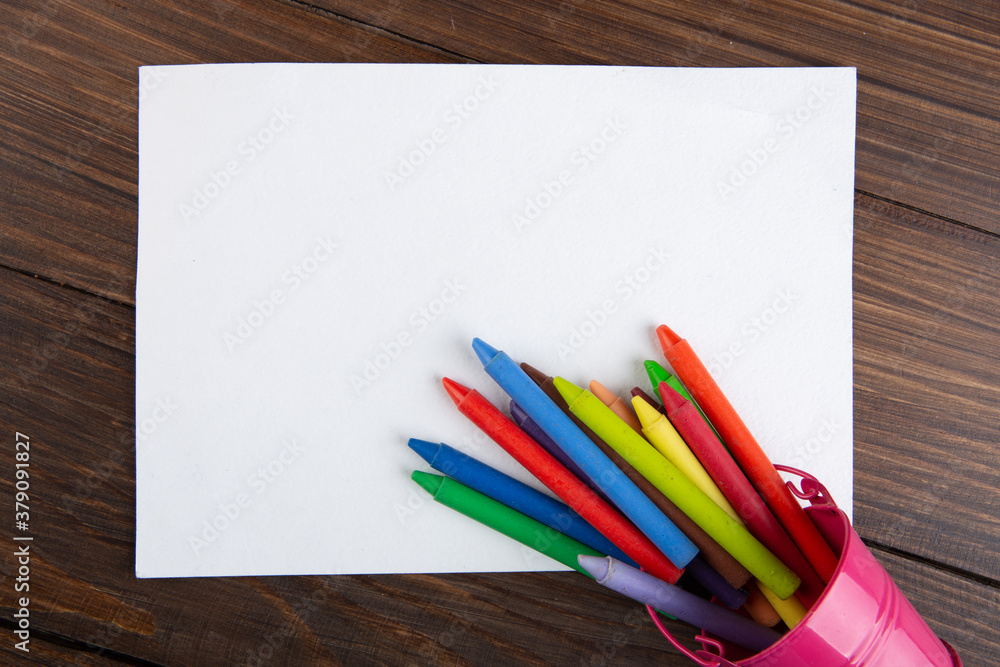 colored crayons and blank page on the wooden table