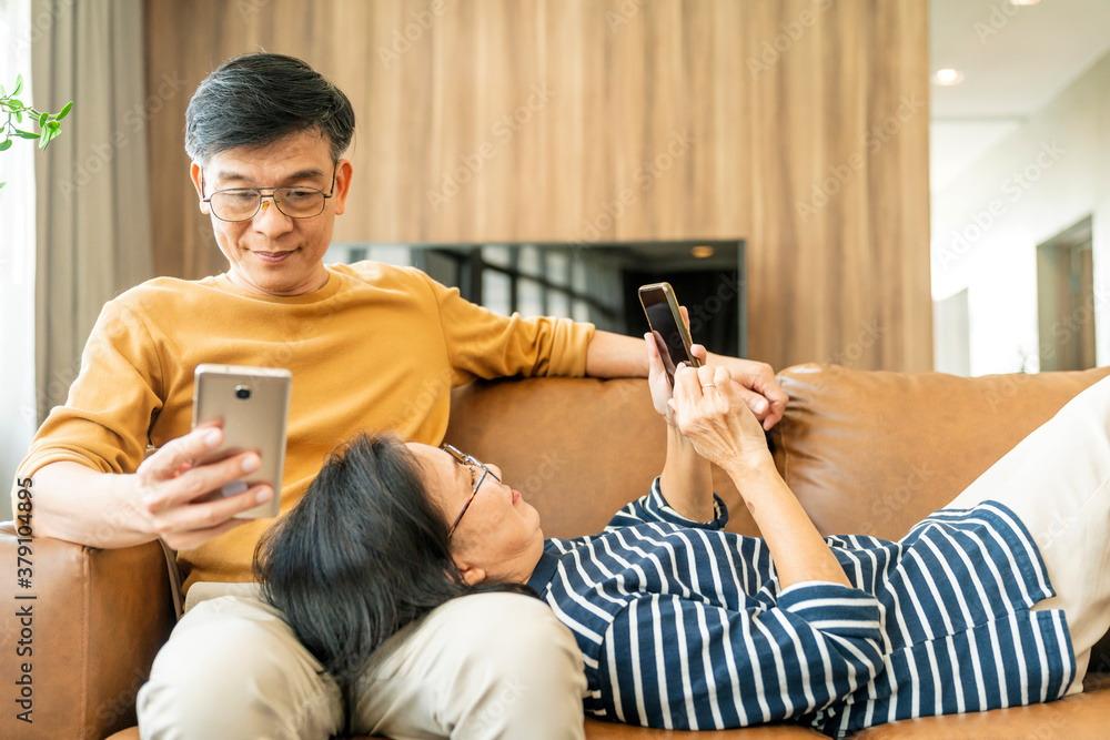 Happy senior old asian lover couple holding smartphone looking at cellphone screen laughing casual r