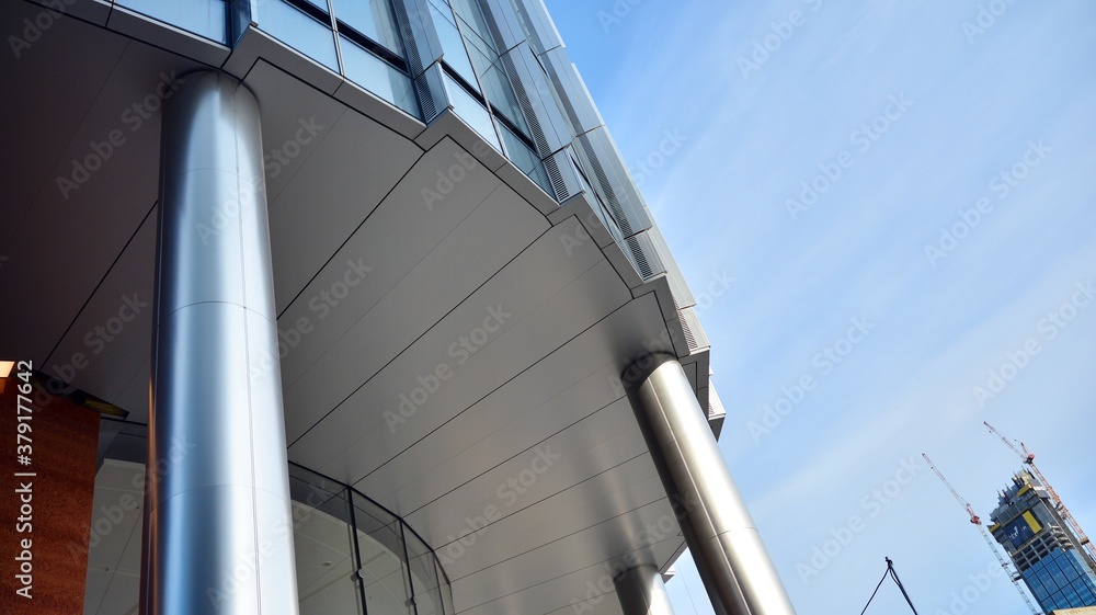 Blue curtain wall made of toned glass and steel constructions under blue sky. A fragment of a buildi