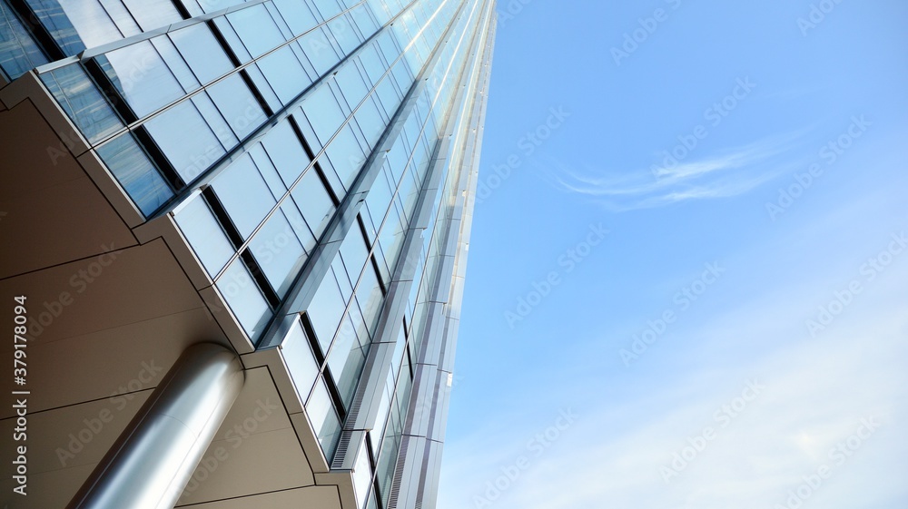 Blue curtain wall made of toned glass and steel constructions under blue sky. A fragment of a buildi