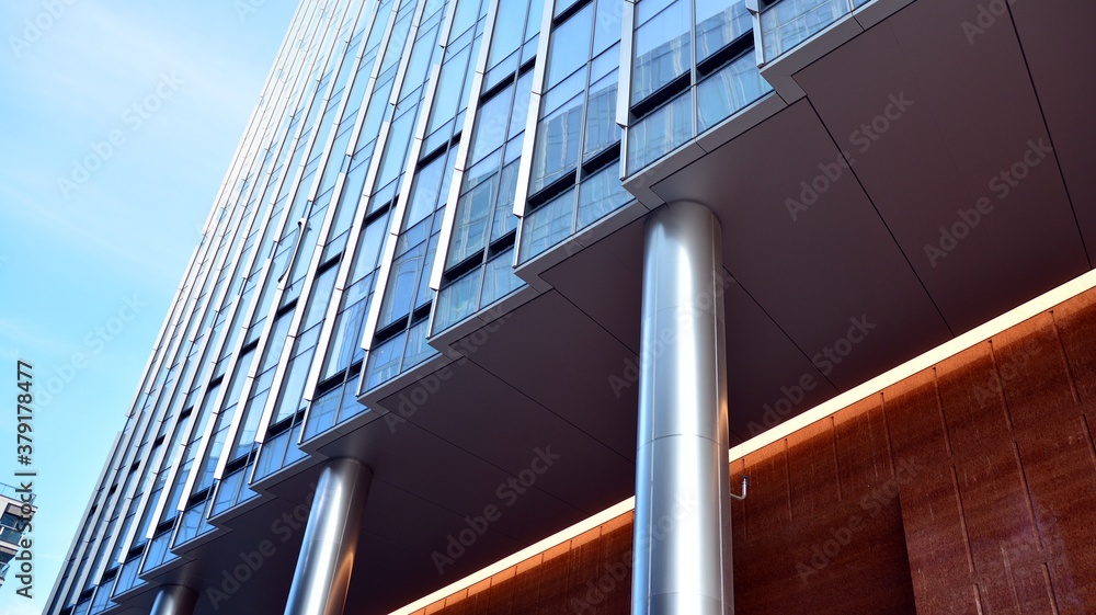 Blue curtain wall made of toned glass and steel constructions under blue sky. A fragment of a buildi