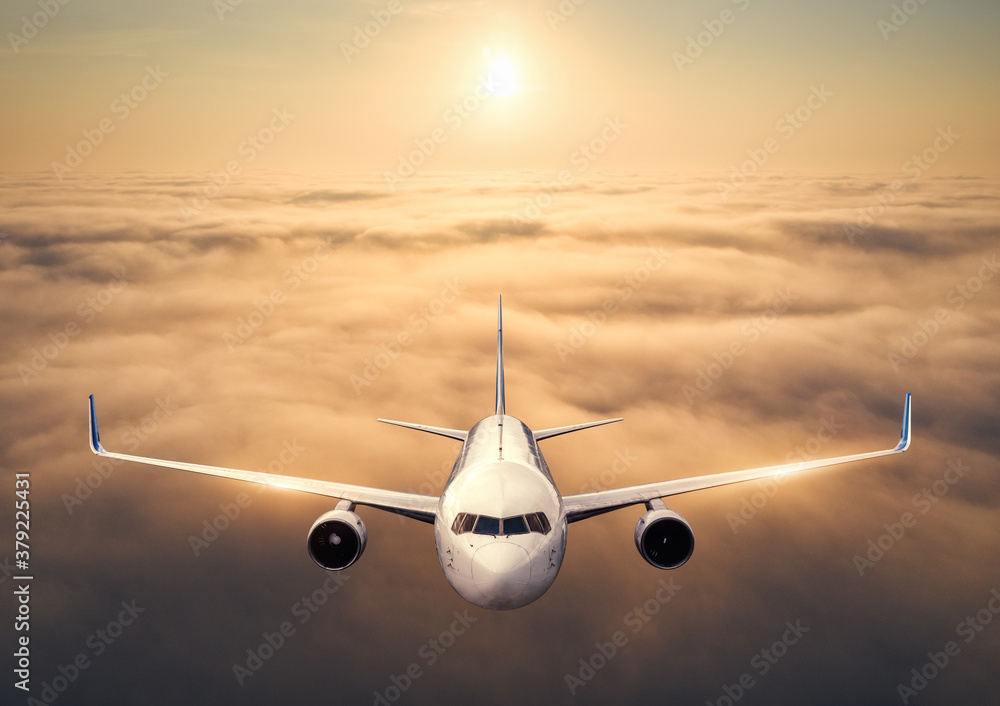 Airplane is flying above the clouds at sunset in summer. Landscape with passenger  airplane, low clo