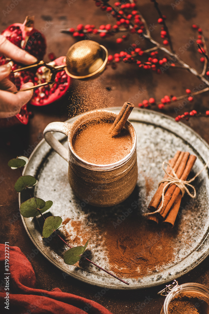 Turkish traditional wintertime hot drink Salep. Human hand pouring cinnamon powder to sweet warming 