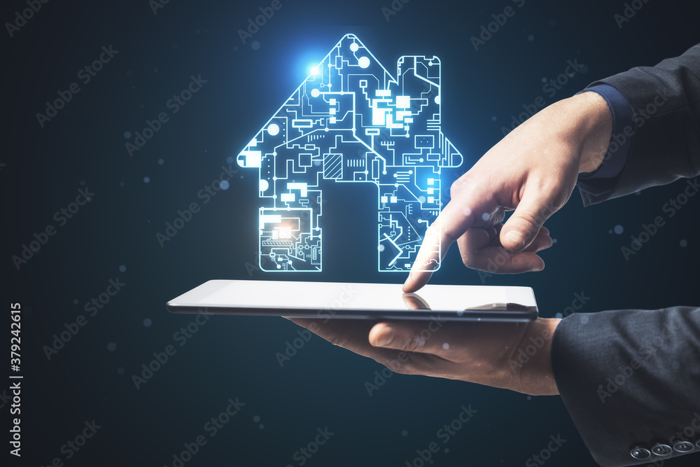 Businessman using tablet with digital circuit house hologram.