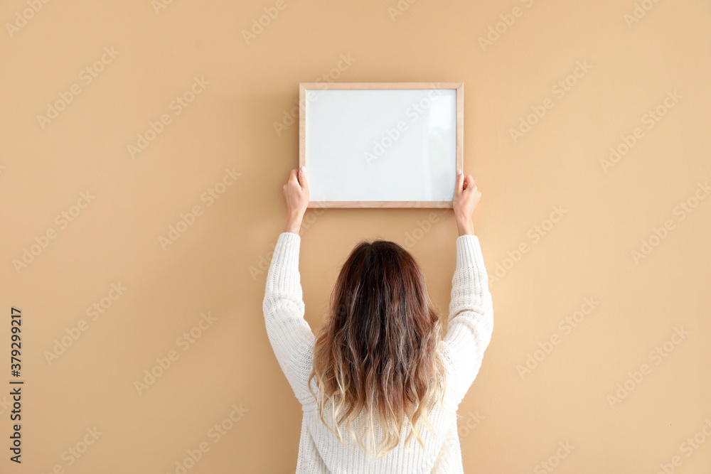 Woman hanging blank photo frame on wall