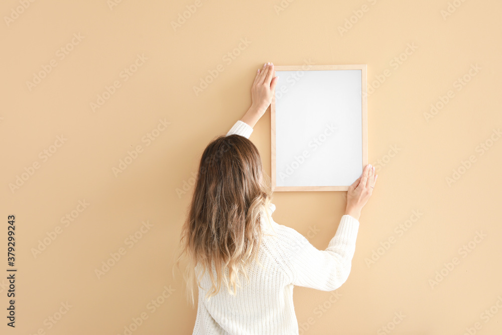 Woman hanging blank photo frame on wall