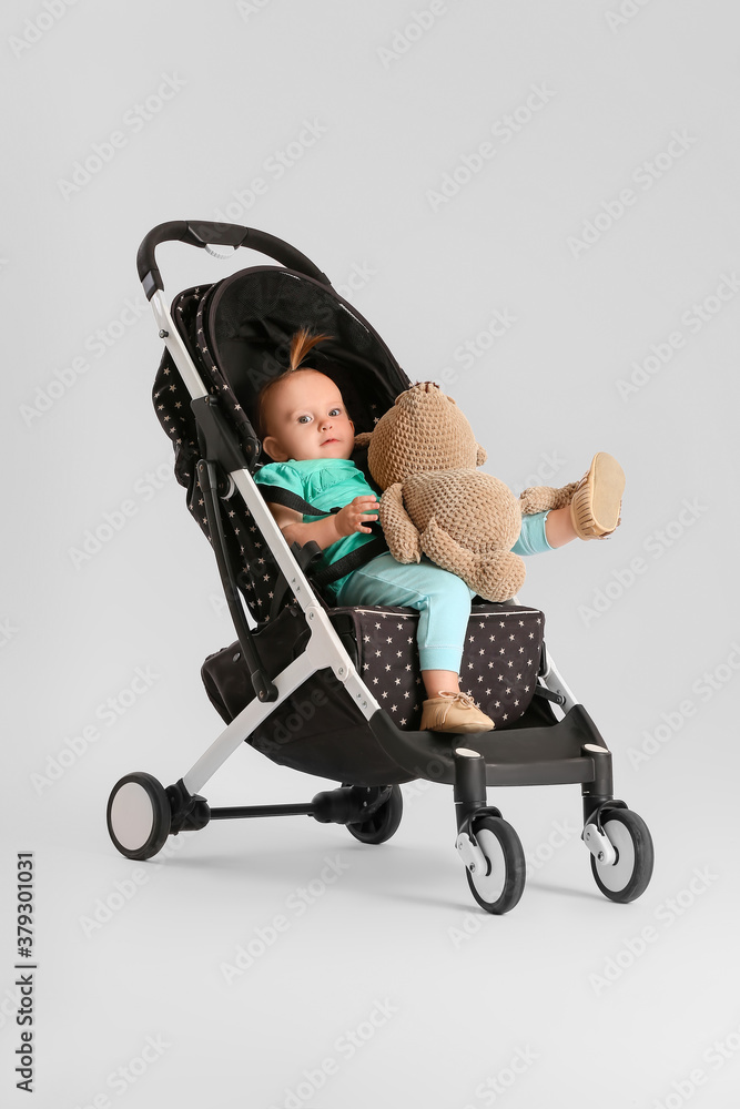 Cute little baby in stroller on light background