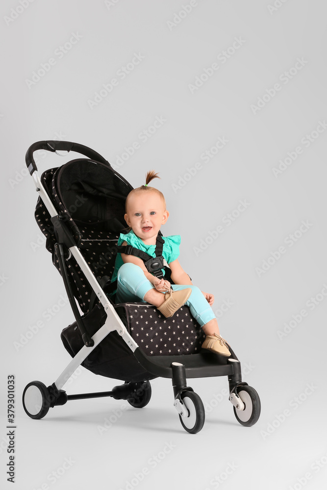 Cute little baby in stroller on light background