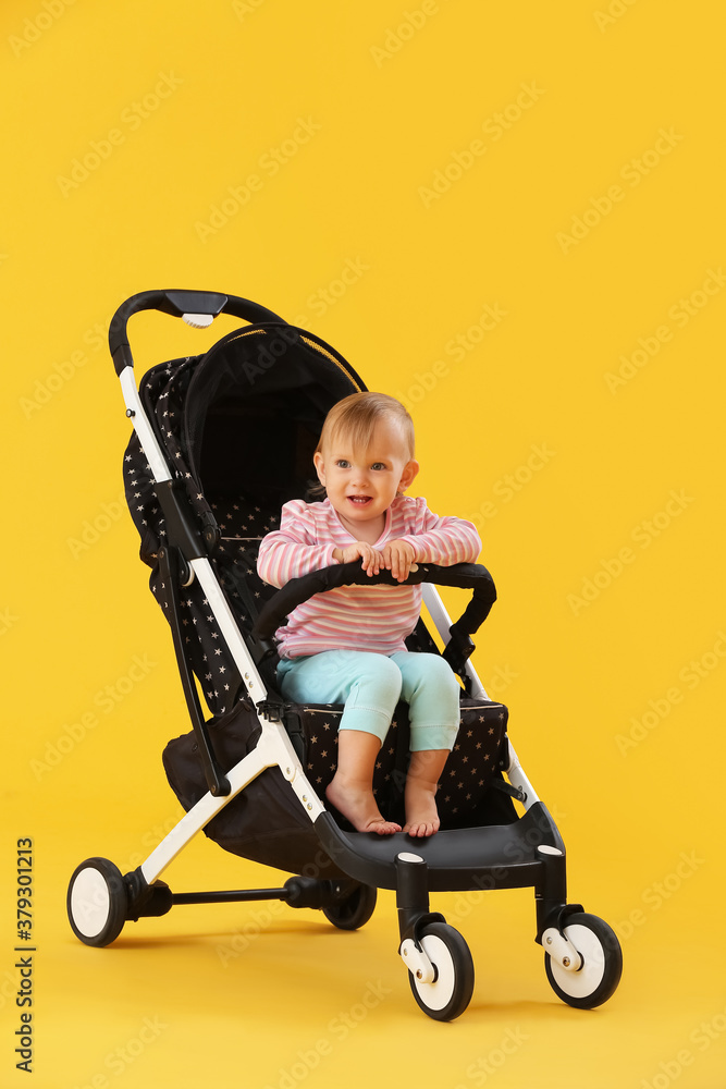 Cute little baby in stroller on color background