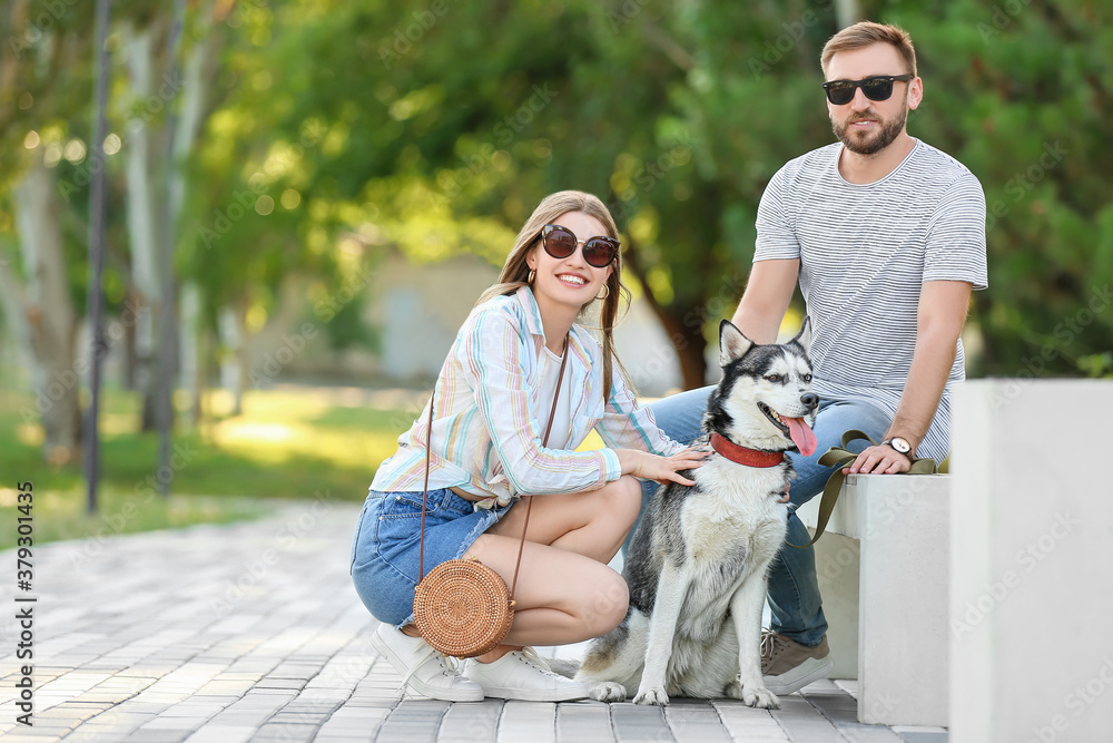 Young couple with cute Husky dog in park