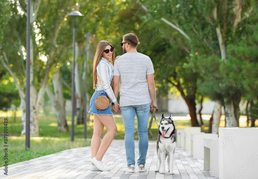 Young couple with cute Husky dog in park