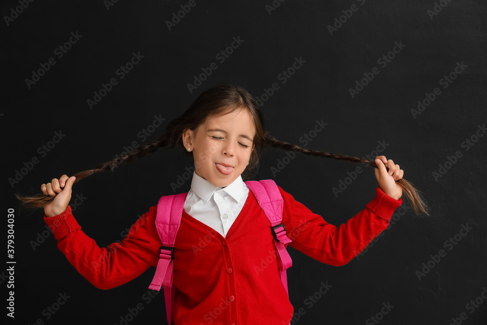 Grimacing little schoolgirl on dark background