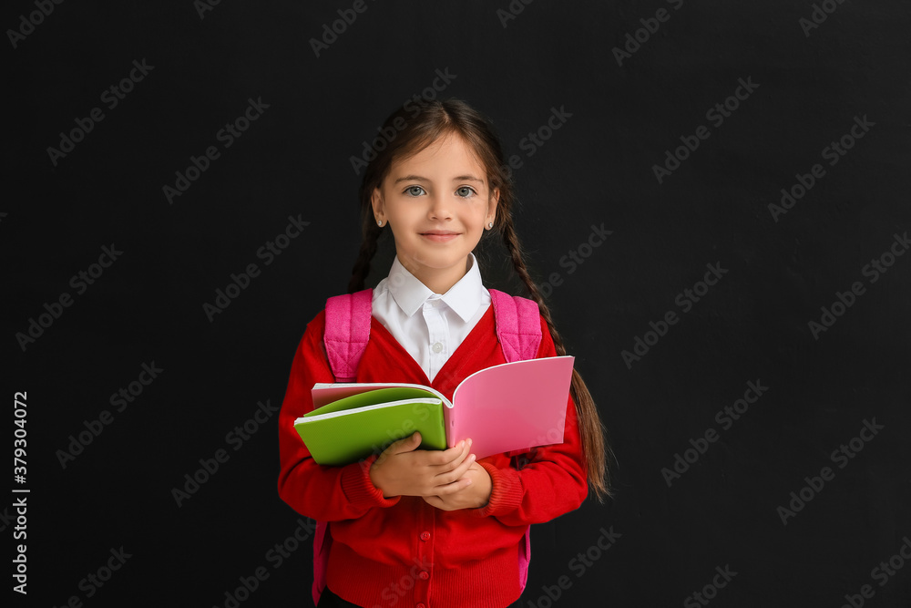 Little schoolgirl with copybook on dark background