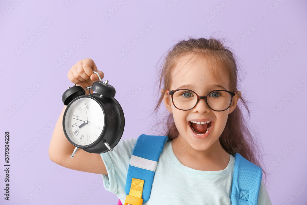 Little schoolgirl with alarm clock on color background. Time to study