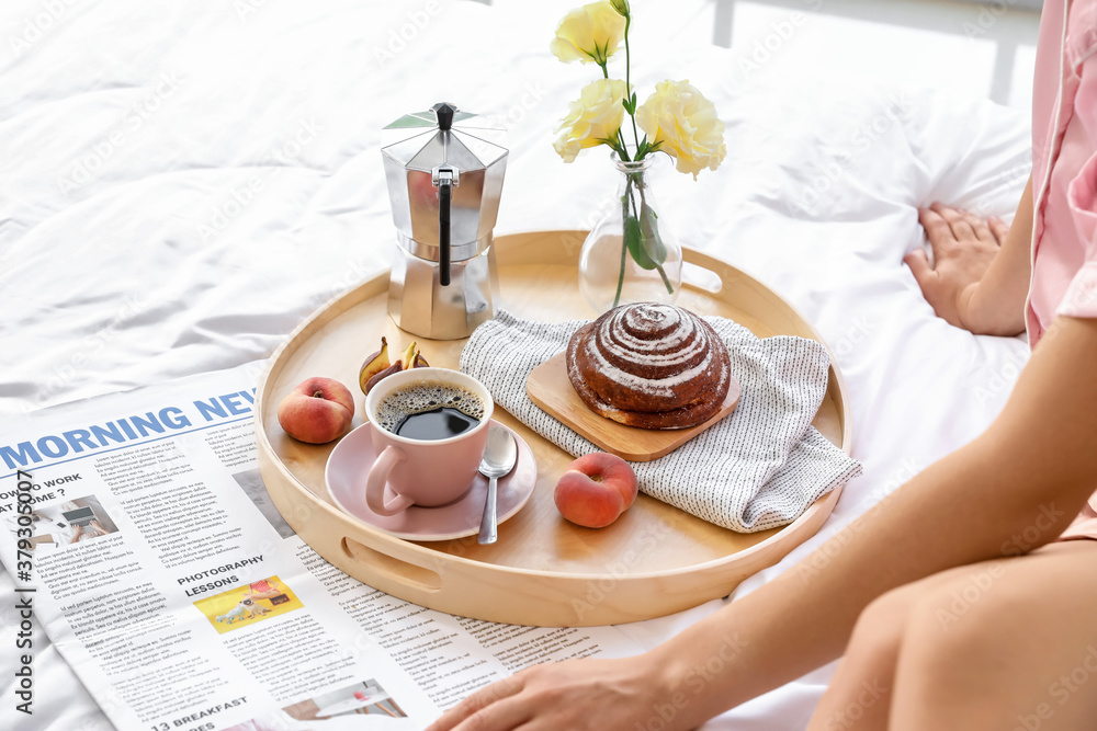 Young woman having tasty breakfast in bed