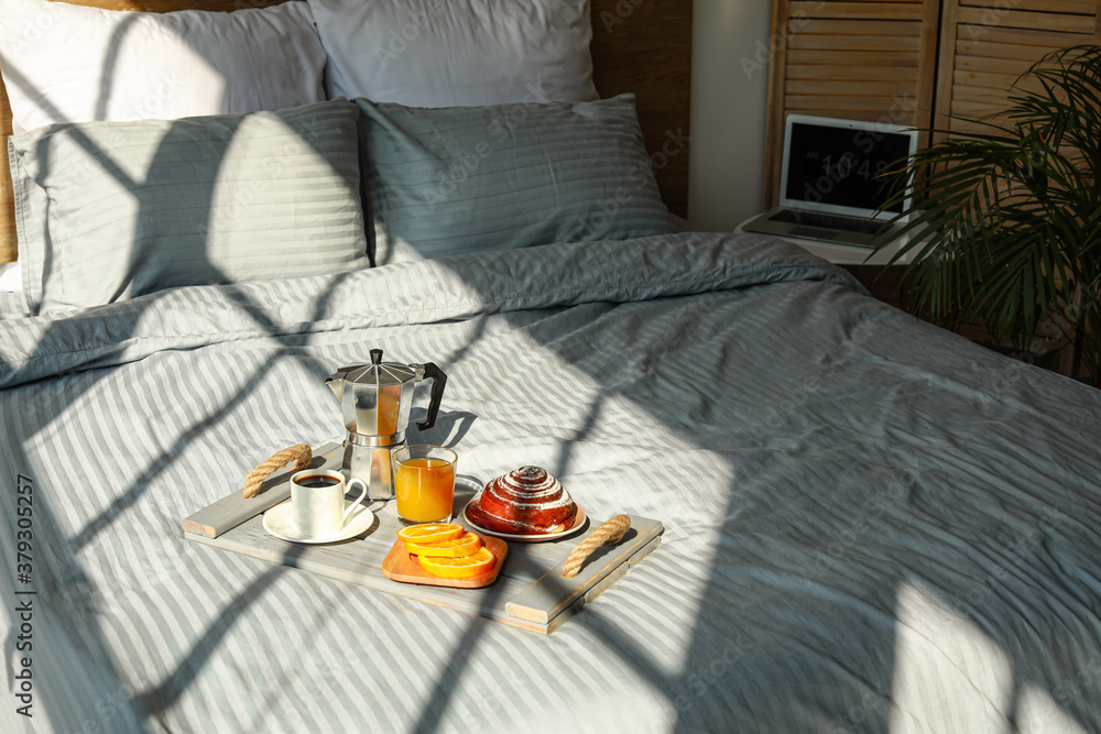 Tray with tasty breakfast on bed