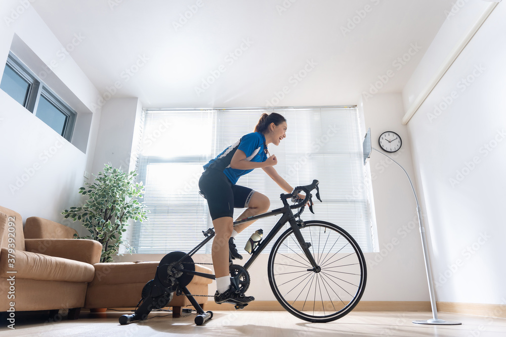 Asian woman cyclist. She is exercising in the house.By cycling on the trainer and play online bike g