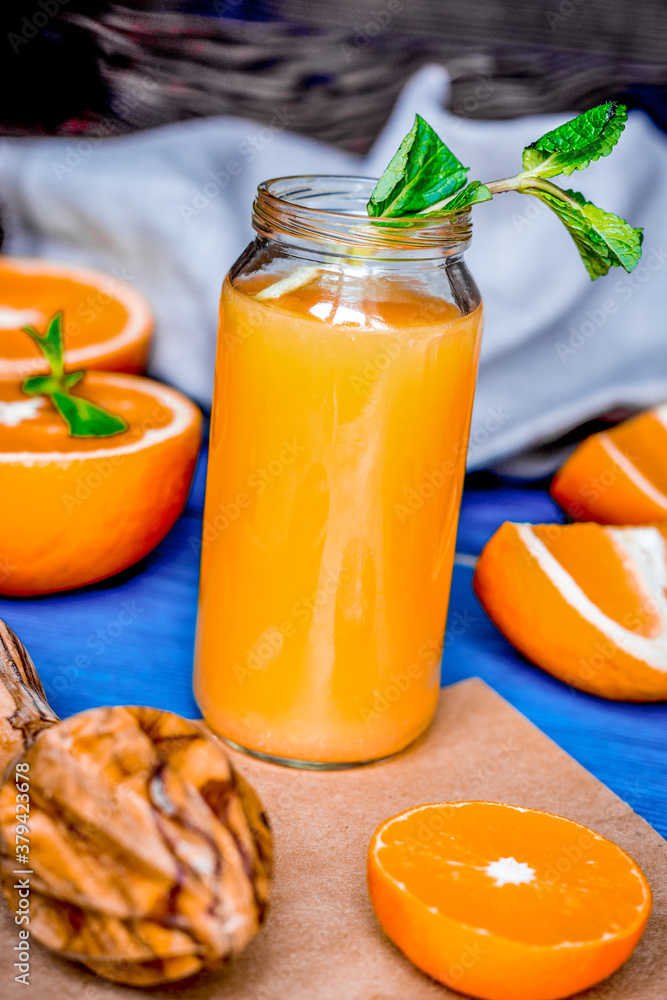 healthy orange cocktail with mint leaves in bottle on kitchen background