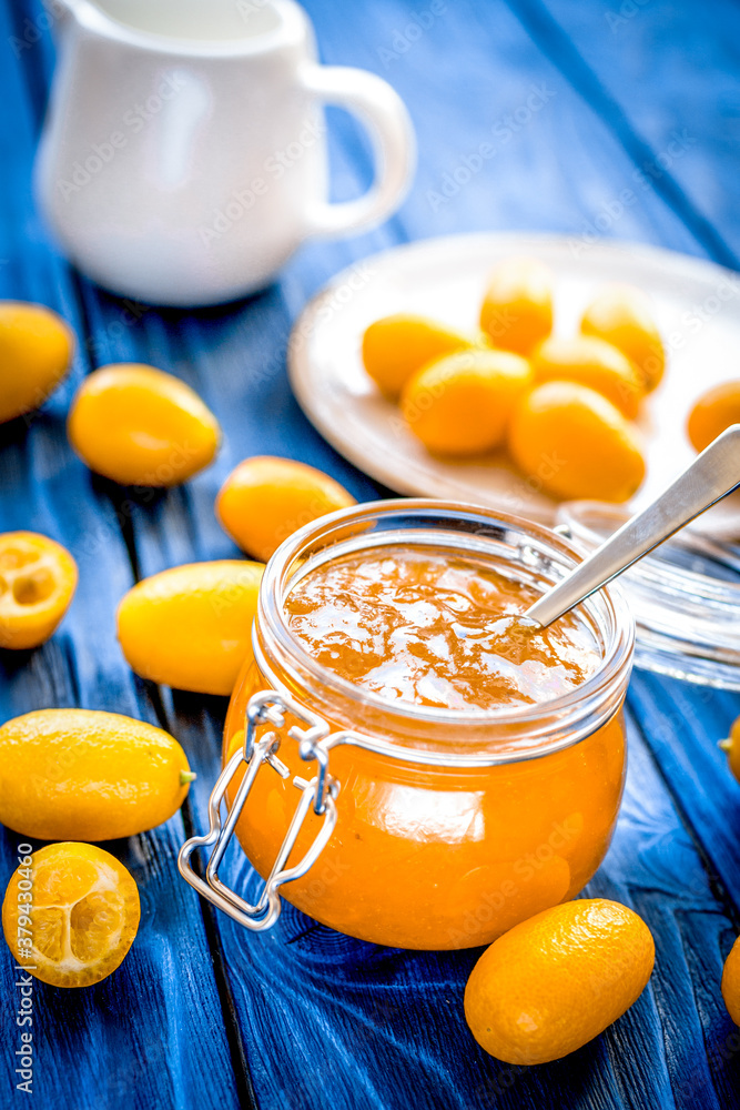 kumquat on plate and jam in jar at wooden table