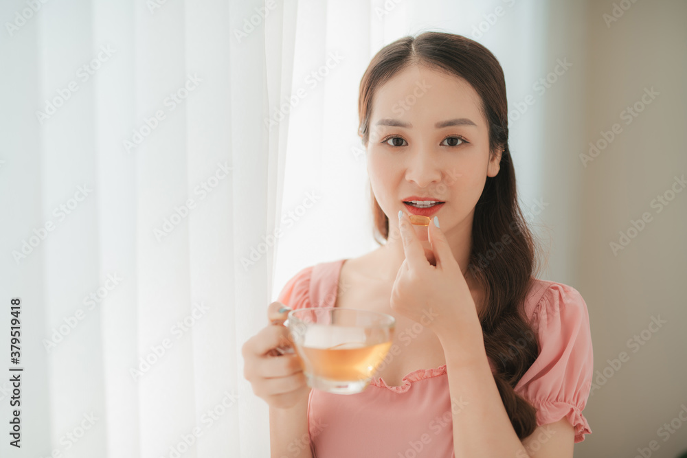 美丽的亚洲女性在家吃营养鱼油补充剂促进健康饮食