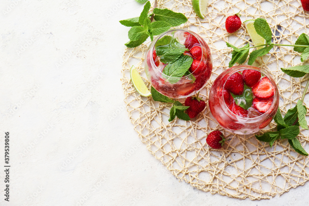 Glasses of fresh strawberry mojito on light background