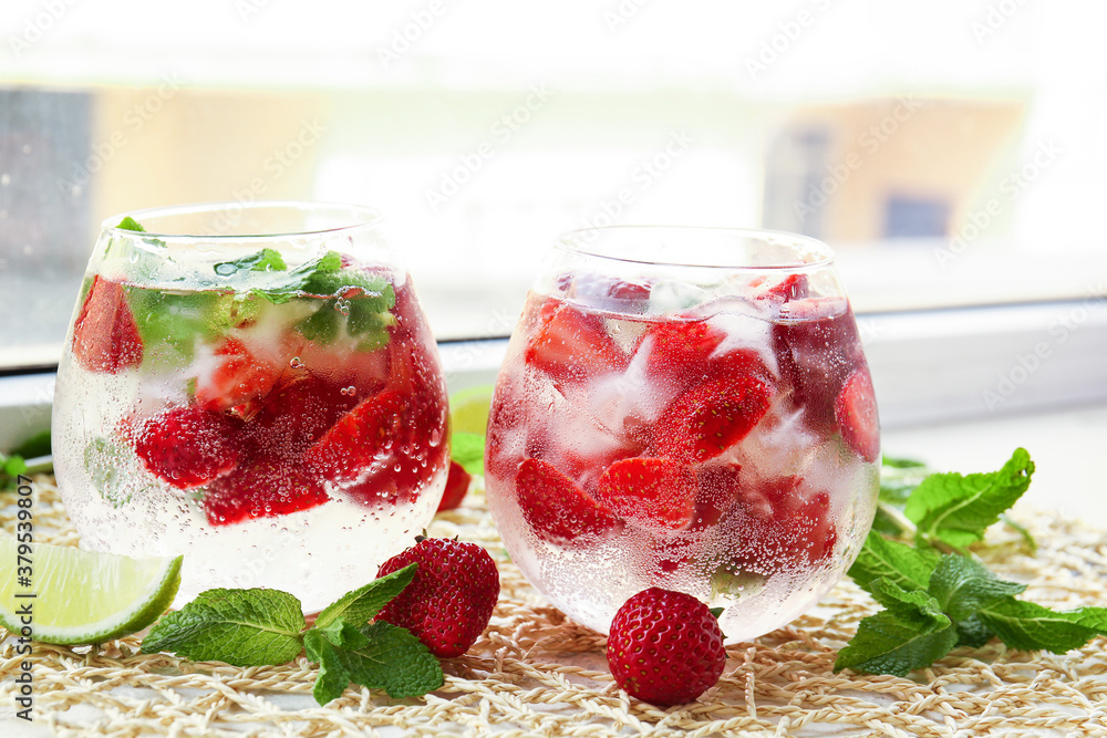 Glasses of fresh strawberry mojito on window sill