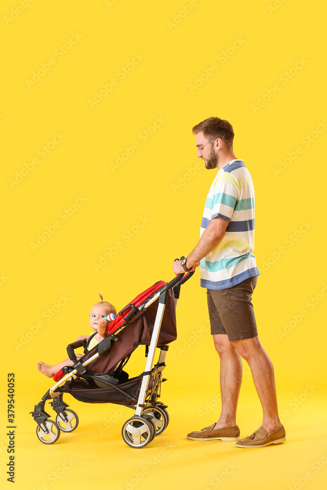 Father and his cute baby in stroller on color background