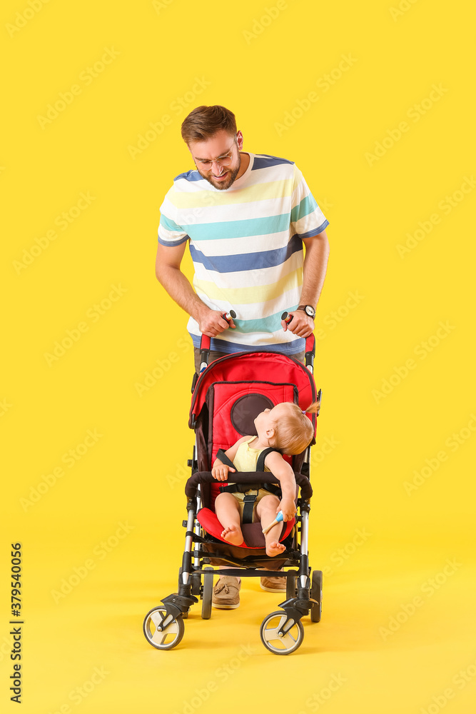 Father and his cute baby in stroller on color background