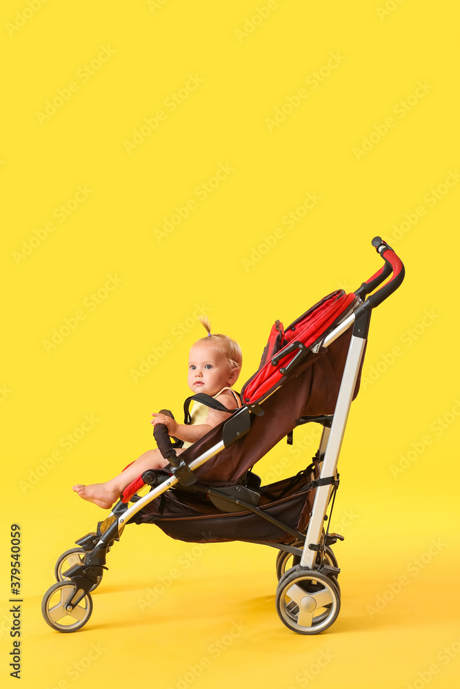 Cute little baby in stroller on color background