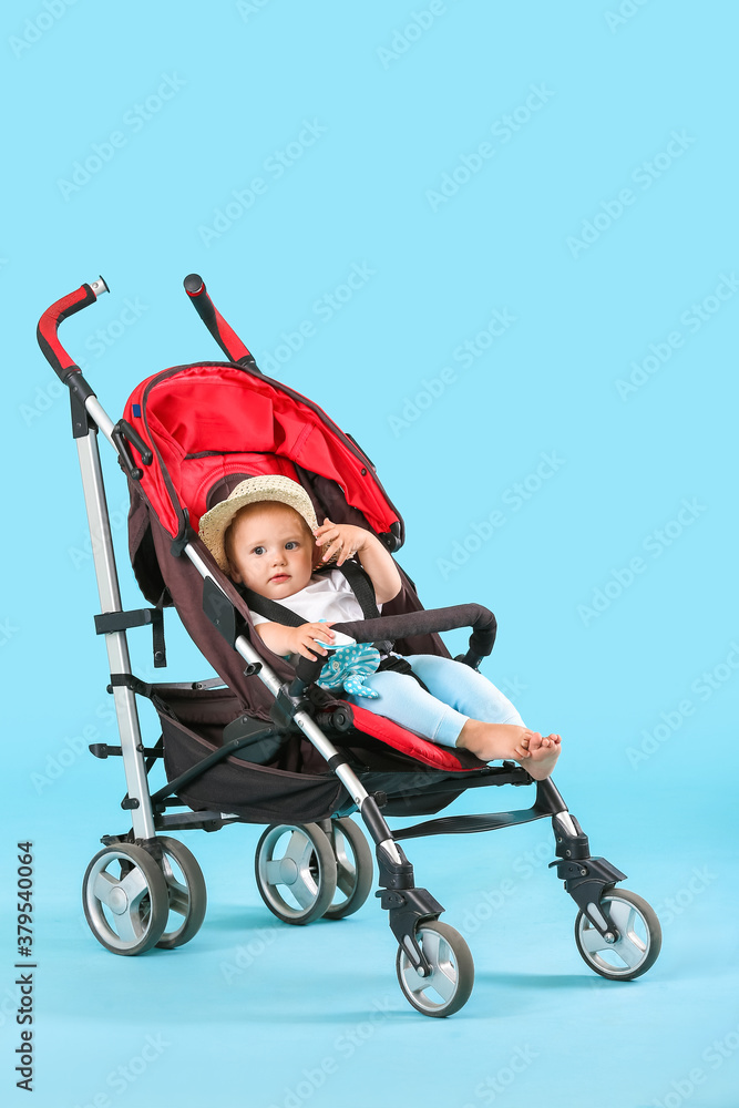 Cute little baby in stroller on color background