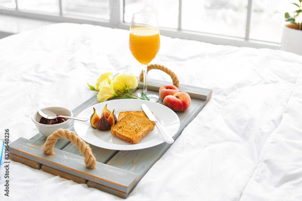 Tray with tasty breakfast on bed