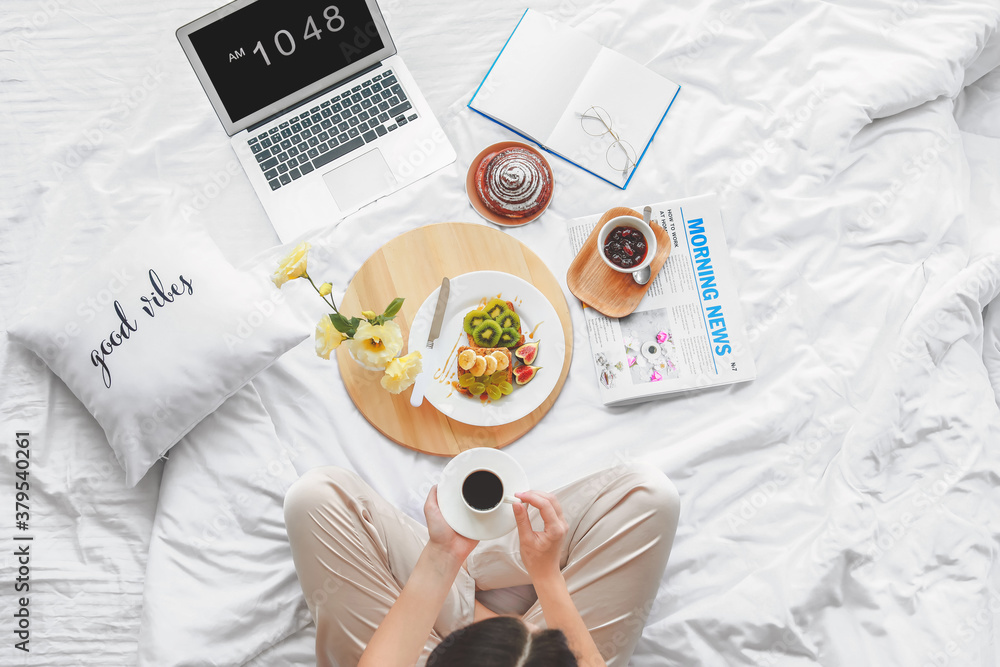 Young woman having tasty breakfast in bed