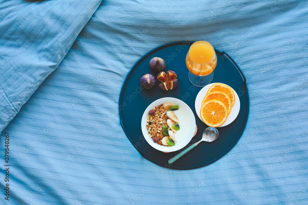 Tray with tasty breakfast on bed