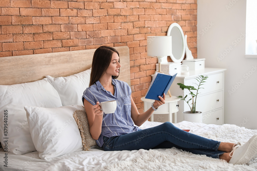 Beautiful young woman reading book at home