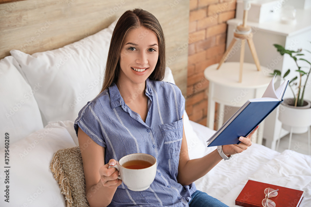 Beautiful young woman reading book at home