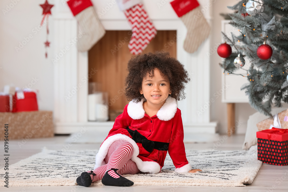 Cute African-American girl in Santa costume at home on Christmas eve