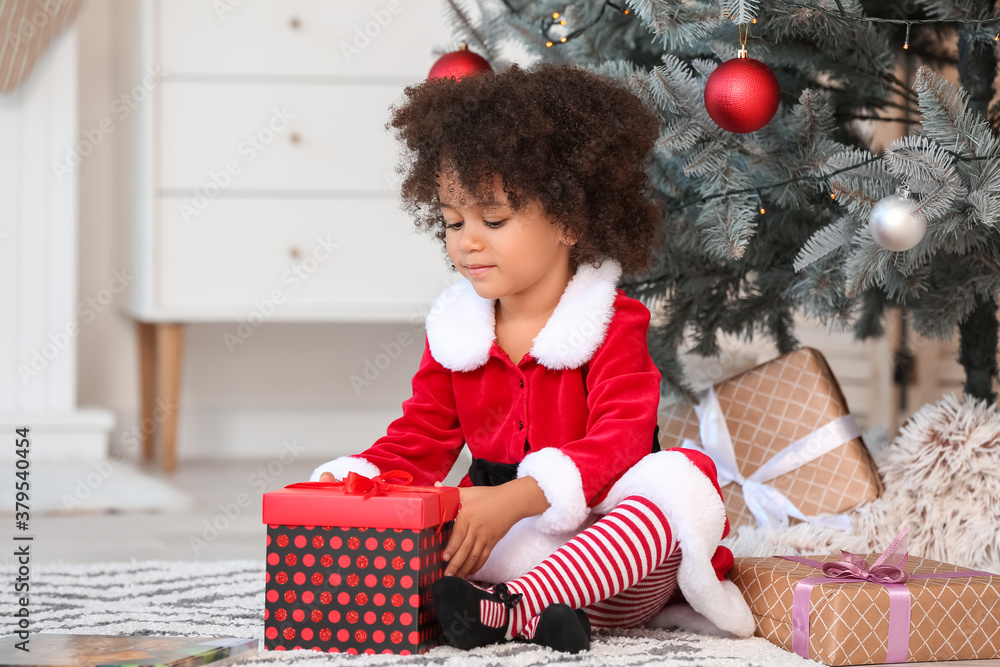 Cute African-American girl with Christmas gifts at home