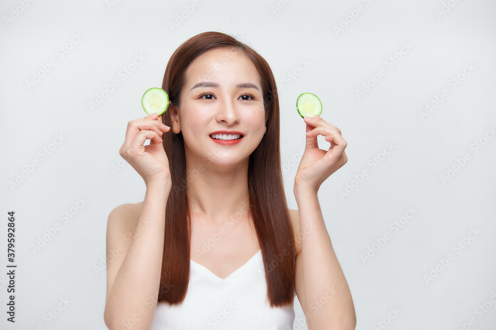 Eco cosmetics. A smiling woman applying an organic cucumber face mask